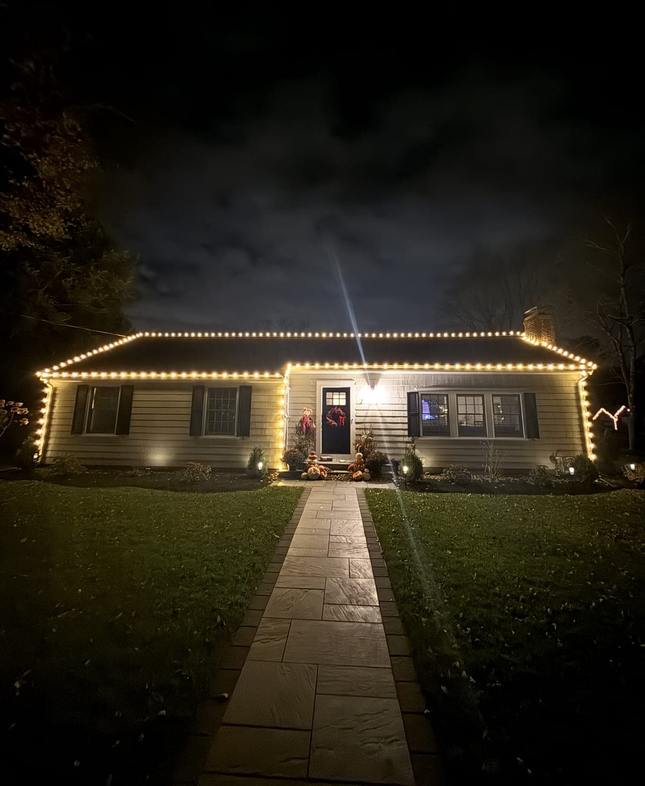 Ranch home with a continuous warm-white roofline, lit wreath and lantern over the front door